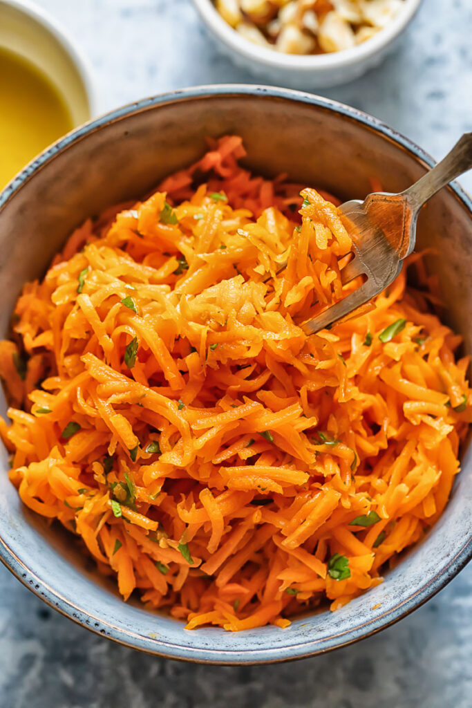 Close up shot of a bowl of french carrot salad with a fork