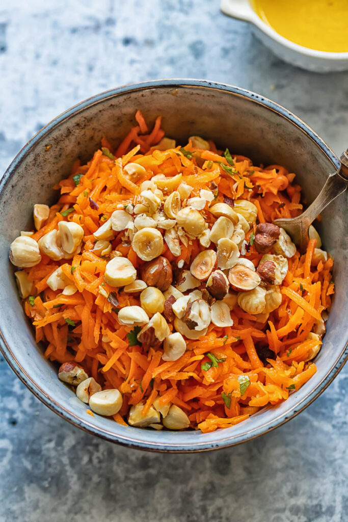 Top down shot of carrot salad in a bowl topped with hazelnuts