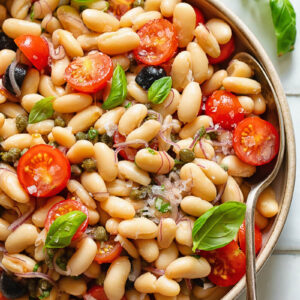 Top down shot of white bean salad in a serving bowl with basil garnish