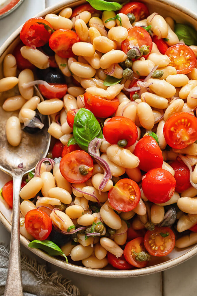 Close up shot of white bean salad with a serving spoon