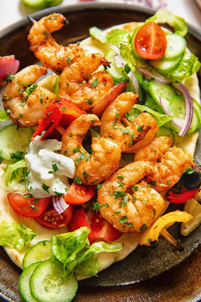 Close up shot of shrimp kebab on pita with salad