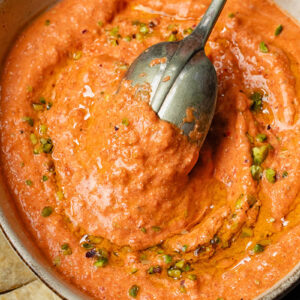 Top down shot of cottage cheese and red pepper dip in a bowl with a spoon