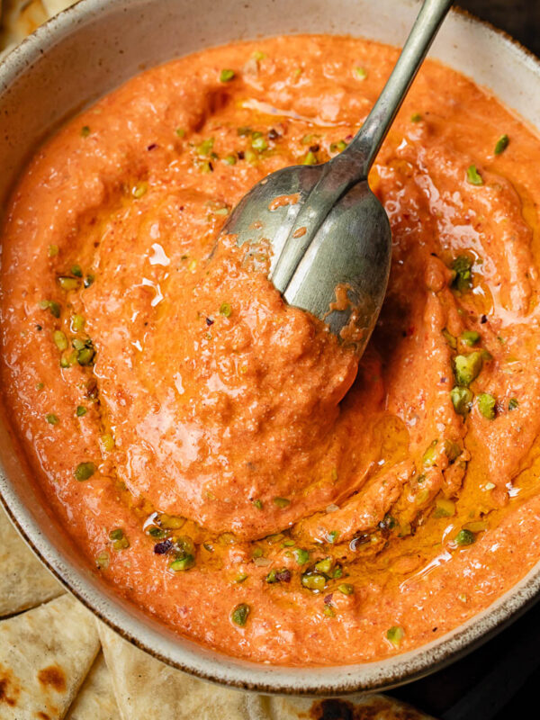 Top down shot of cottage cheese and red pepper dip in a bowl with a spoon