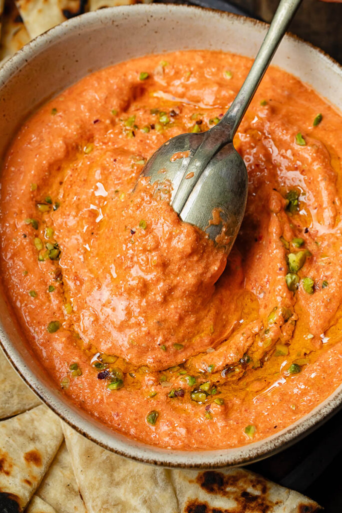 Top down shot of cottage cheese and red pepper dip in a bowl with a spoon