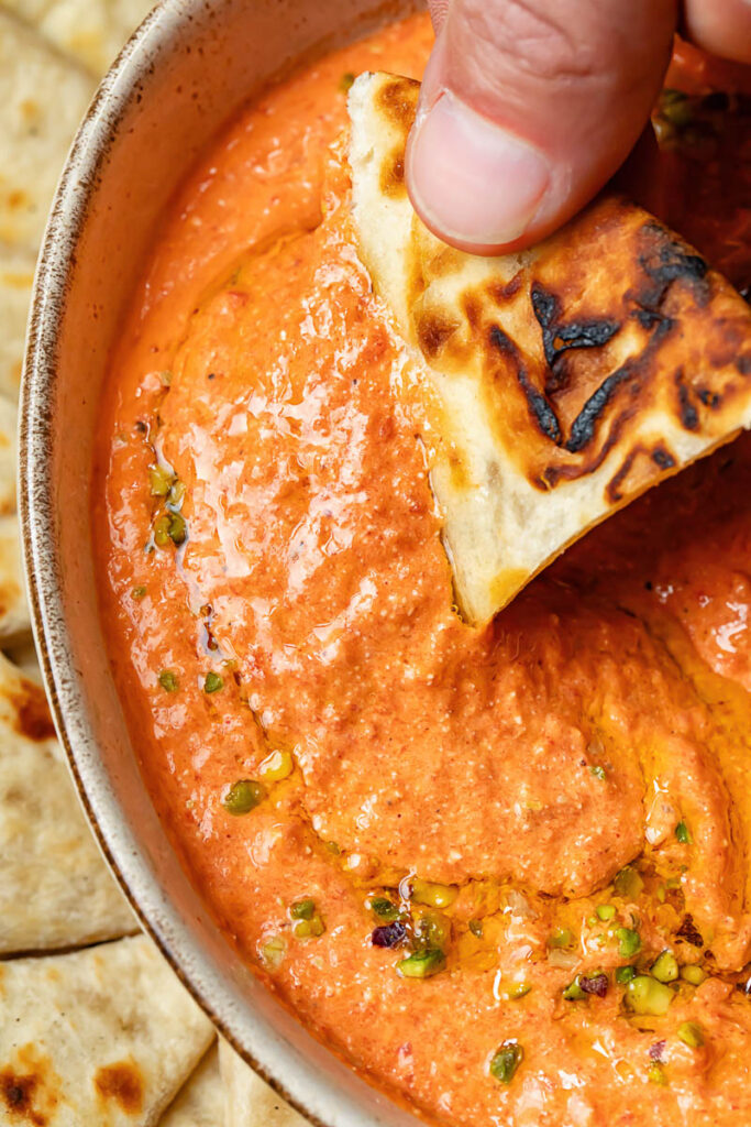 Close up shot of bread dipped in red pepper dip