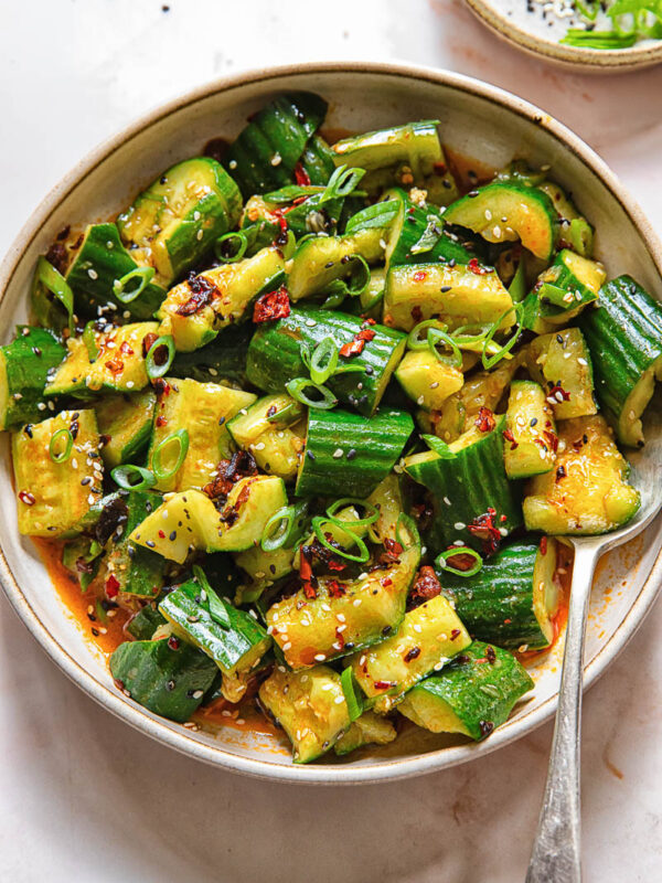 Top down shot of smashed cucumber salad in a bowl with a spoon