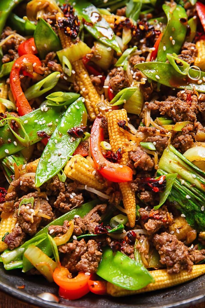 Close up shot of beef stir fry with snow peas, peppers and baby corn