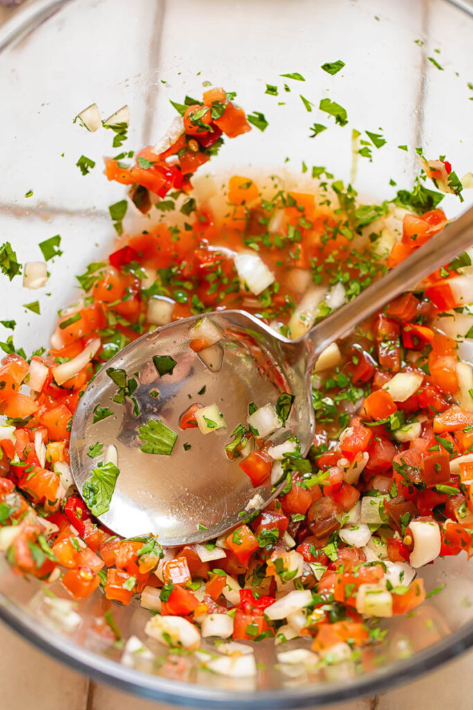 Top down shot of pico de gallo in a bowl with a serving spoon