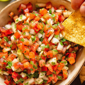 Close up shot of tortilla chip dipped in pico de gallo