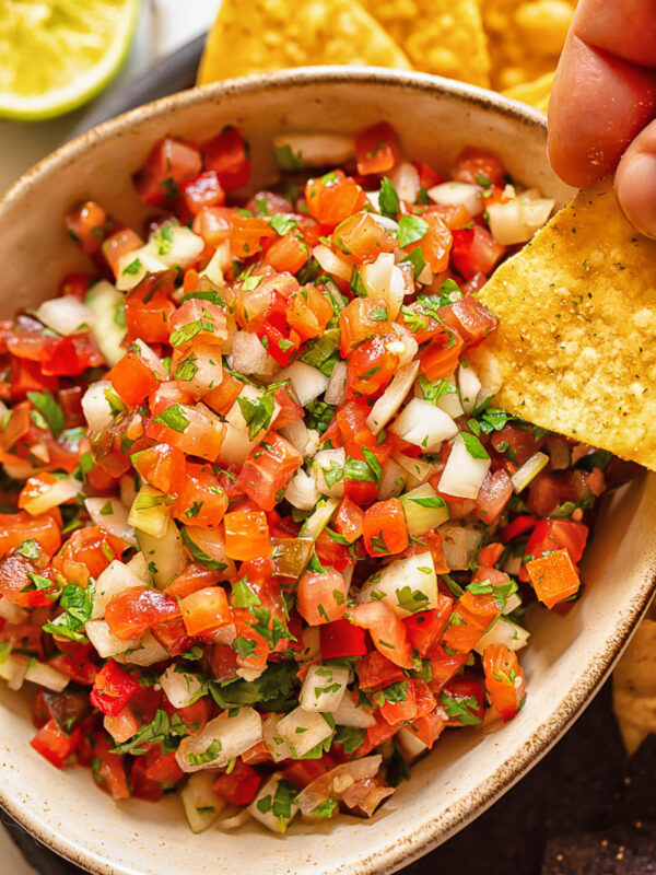Close up shot of tortilla chip dipped in pico de gallo