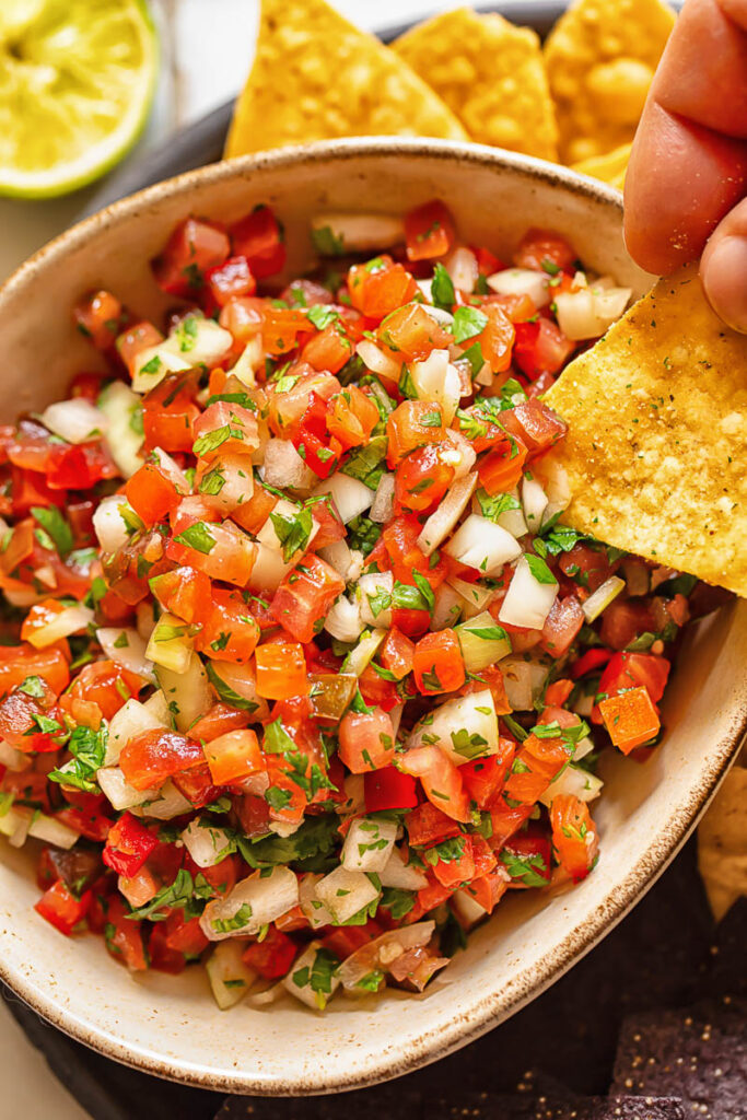 Close up shot of tortilla chip dipped in pico de gallo