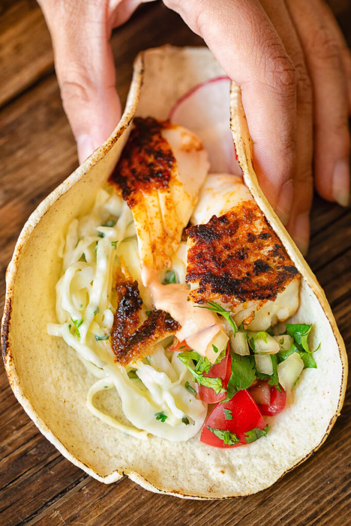 hand folding a corn taco with filling