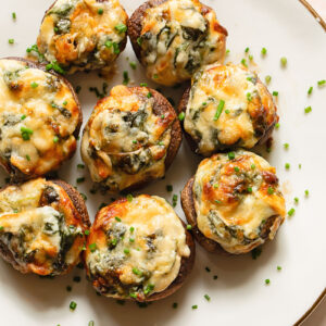spinach dip stuffed mushrooms on a plate topped with chives