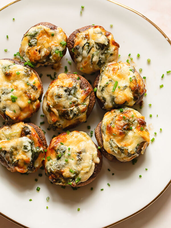spinach dip stuffed mushrooms on a plate topped with chives