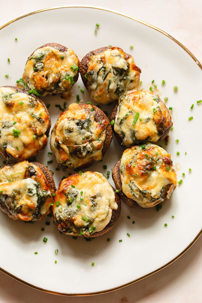 spinach dip stuffed mushrooms on a plate topped with chives