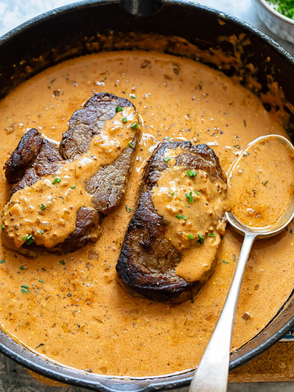 Steak Diane fillets in a cast iron pan with a spoon
