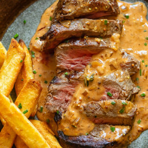Steak Diane on a plate with fries and creamy sauce