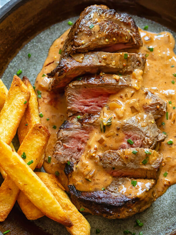 Steak Diane on a plate with fries and creamy sauce