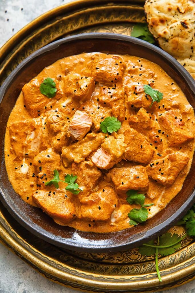 Close up shot of butter salmon curry topped with cilantro