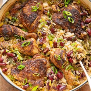 Top down shot of Jamaican chicken with rice and peas in a pan with a serving spoon