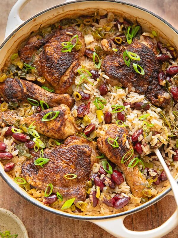 Top down shot of Jamaican chicken with rice and peas in a pan with a serving spoon