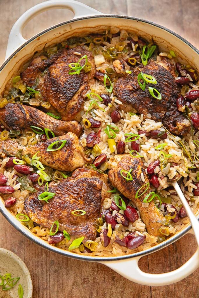 Top down shot of Jamaican chicken with rice and peas in a pan with a serving spoon