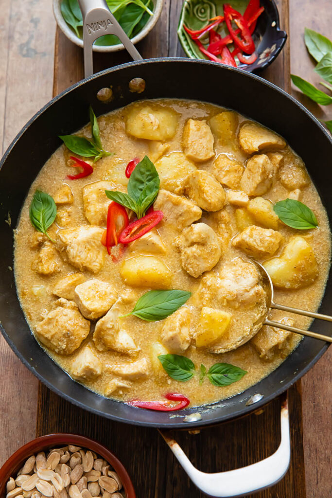Close up of yellow chicken curry with potatoes and chilli in a pot