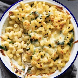 white dish with a blue border holding a baked mac and cheese with kale