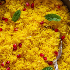 Close up of saffron rice topped with pomegranate