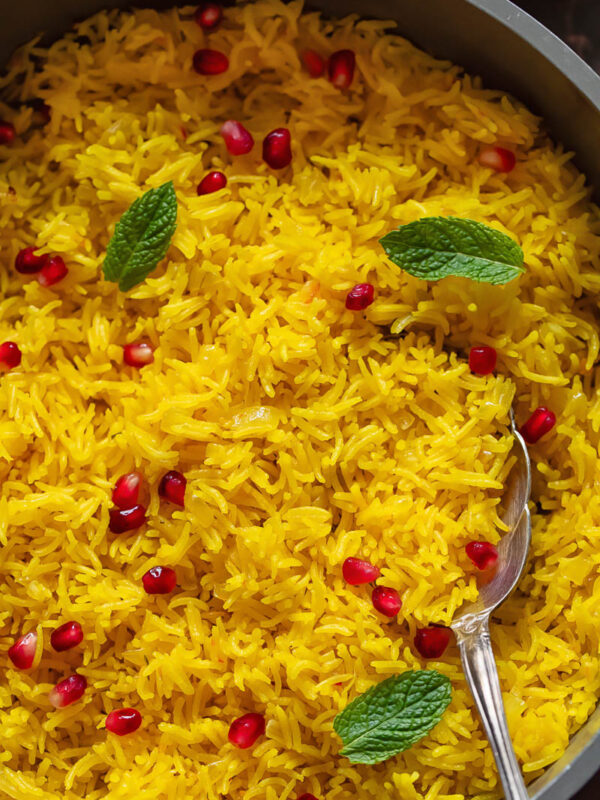 Close up of saffron rice topped with pomegranate