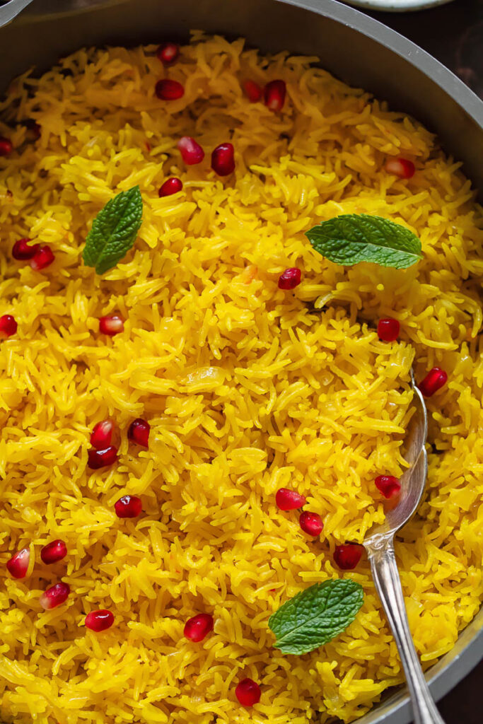 Close up of saffron rice topped with pomegranate