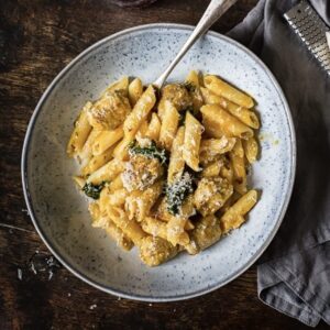 bowl of pasta with meatballs and shredded parmesan with a fork