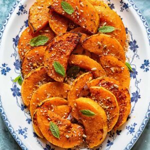 roasted butternut squash slices on a plate with basil garnish