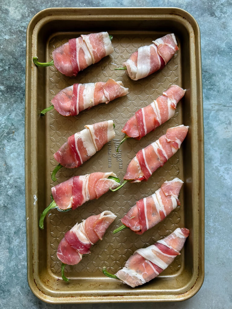 uncooked jalapeno poppers arranged on a baking dish