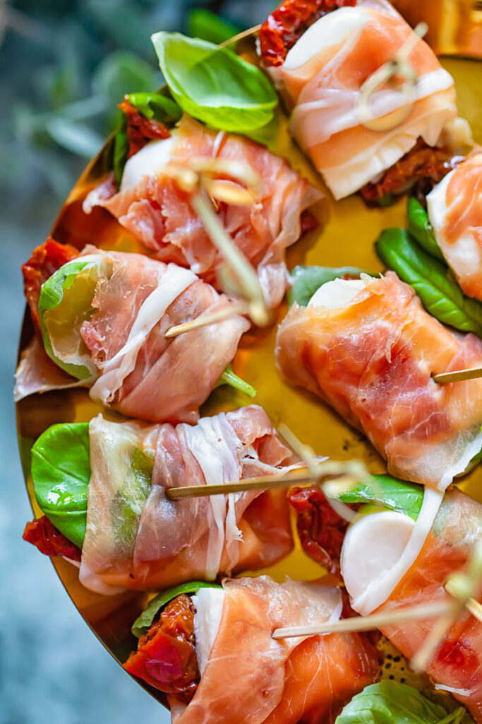 close up of prosciutto caprese bites on a shiny pattern