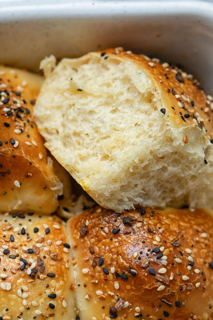 Close up of dinner roll being removed from baking dish
