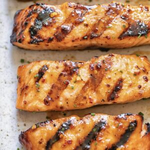 three strips of salmon on a light background with a shiny glaze