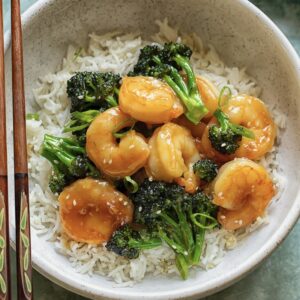 glazed shrimp and broccoli on rice in a bowl with chopsticks
