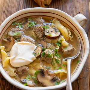 Beef stroganoff soup in a bowl topped with sour cream