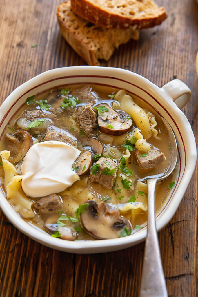 Beef stroganoff soup in a bowl topped with sour cream
