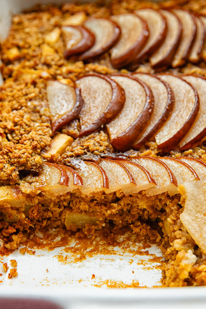 angled view of baked oatmeal in a baking dish with sliced pear on top