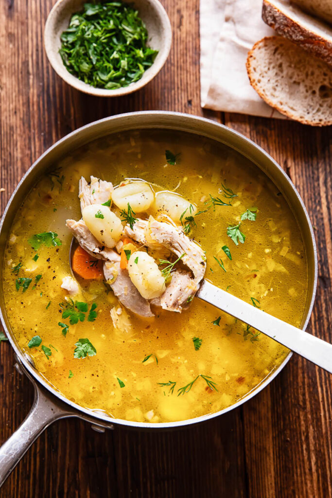 Top down shot of gnocchi soup in a pot with frsh herbs