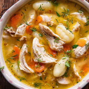 Close up shot of chicken and gnocchi soup in a small bowl