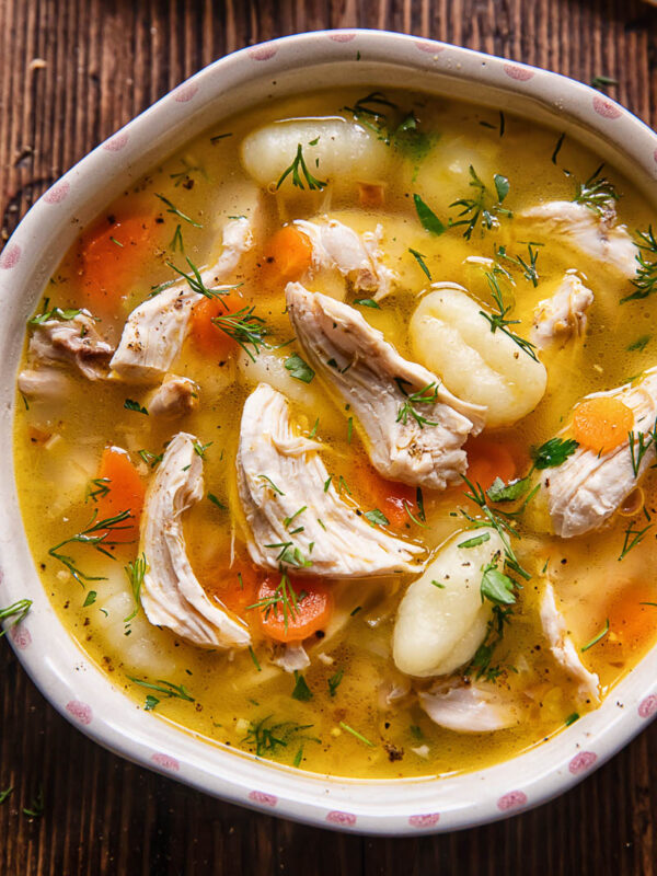 Close up shot of chicken and gnocchi soup in a small bowl
