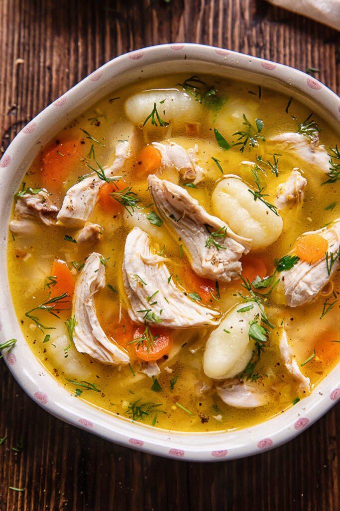 Close up shot of chicken and gnocchi soup in a small bowl