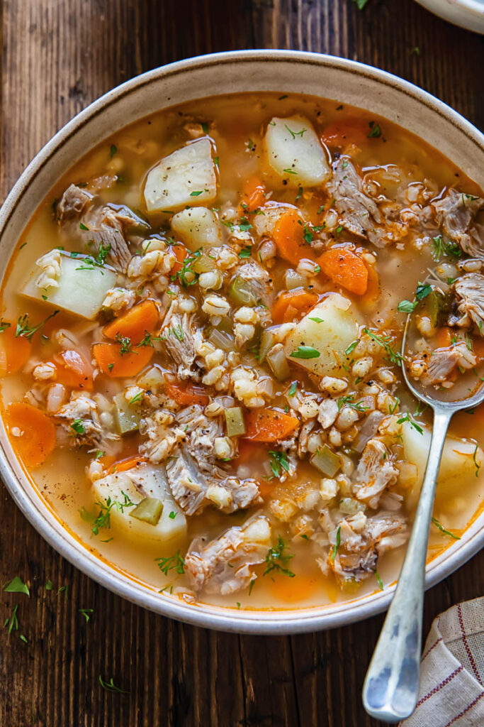 Close up shot of dill pickle soup in a bowl with a spoon