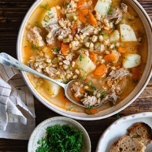 Top down shot of a bowl of dill pickle soup with bread