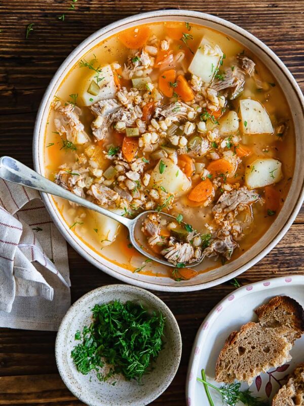 Top down shot of a bowl of dill pickle soup with bread