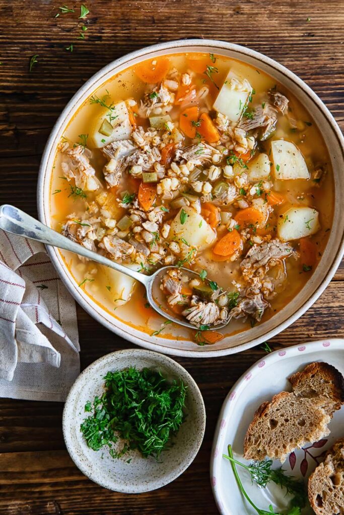 Top down shot of a bowl of dill pickle soup with bread