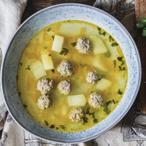 bowl of yellow soup with prominent meatballs